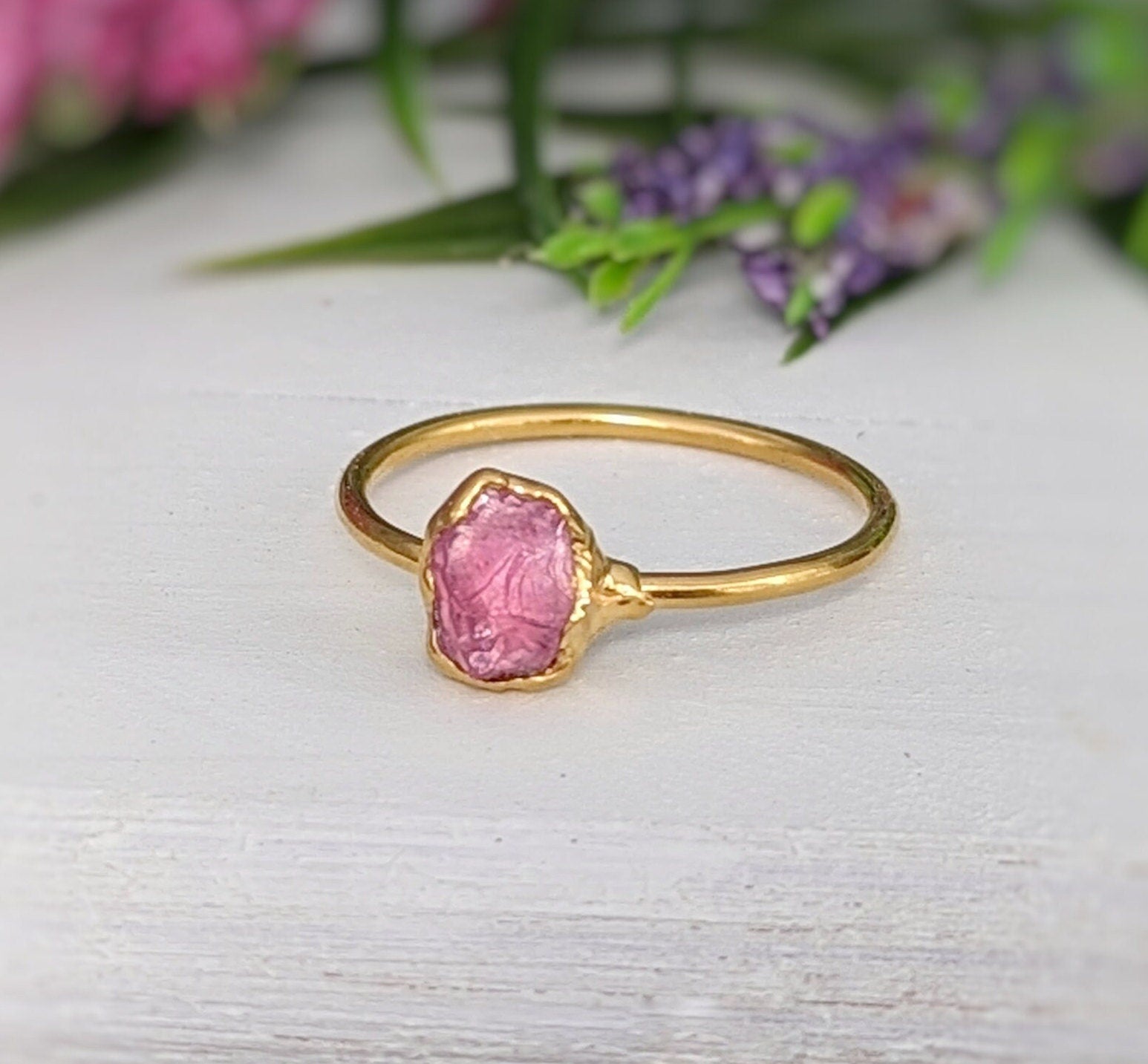 Raw pink spinel ring with uncut edges on a gold band, showcasing natural beauty and earthy elegance.