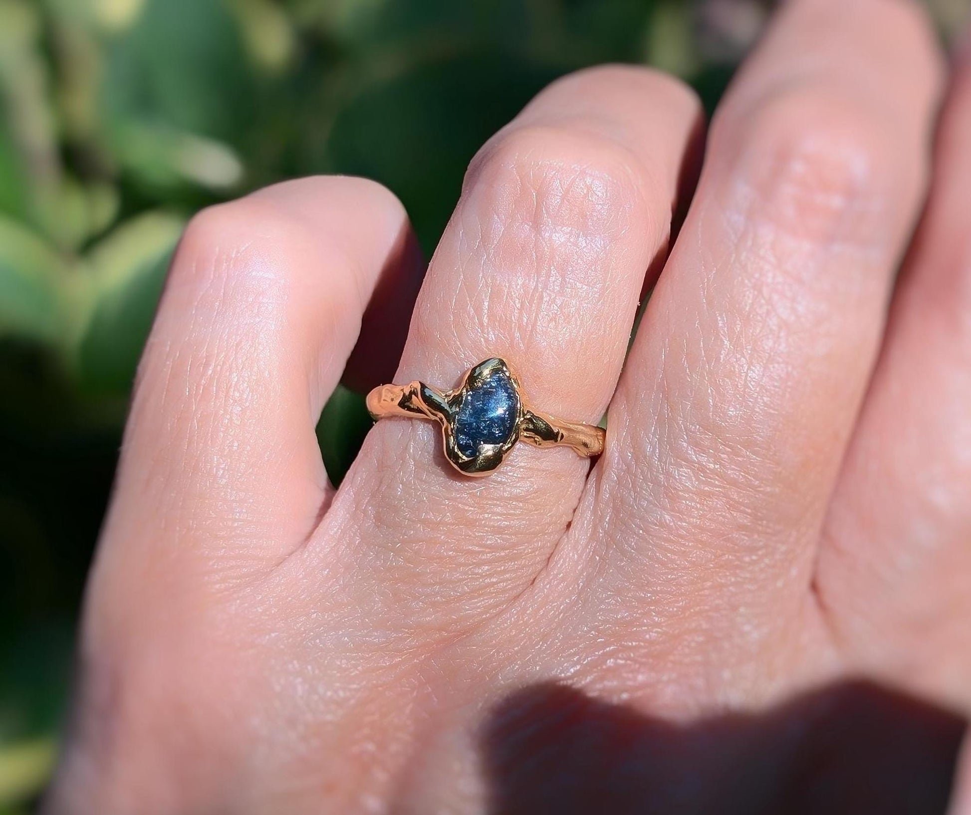 Hand wearing a unique Australian Sapphire ring in solid 14k gold from the 'Pea in a Pod' Collection.