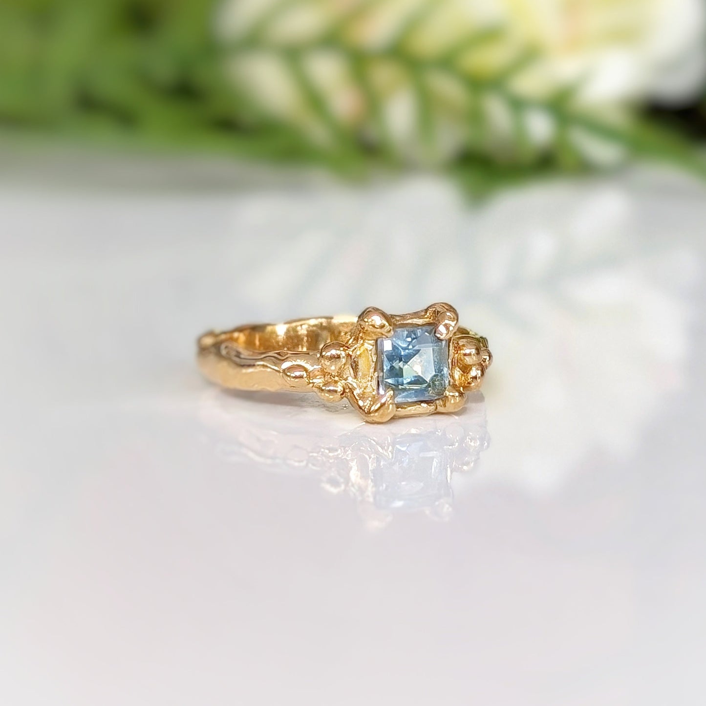 Elegant gold ring featuring a stunning blue topaz gemstone, handcrafted with a unique textured band.