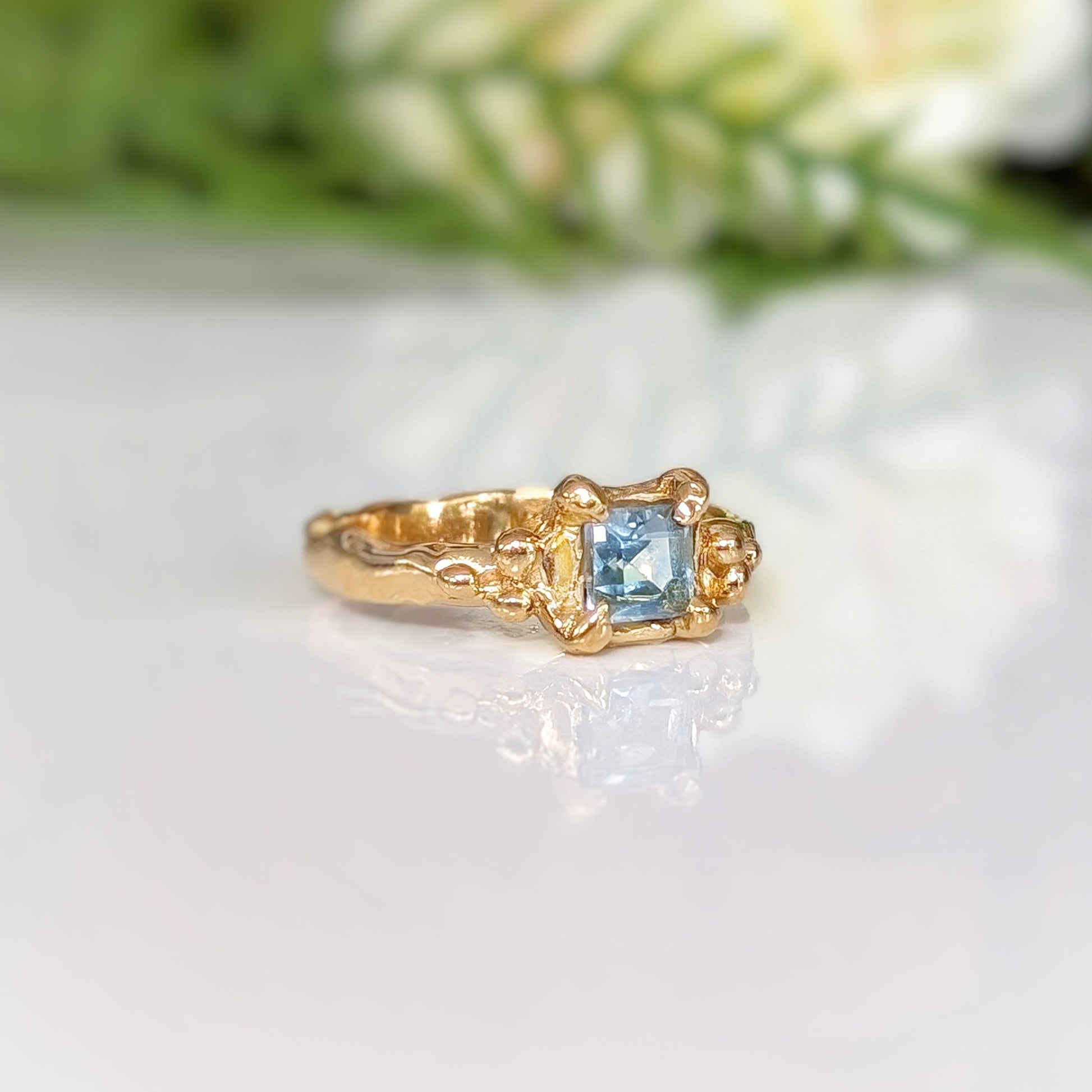 Elegant gold ring featuring a stunning blue topaz gemstone, handcrafted with a unique textured band.