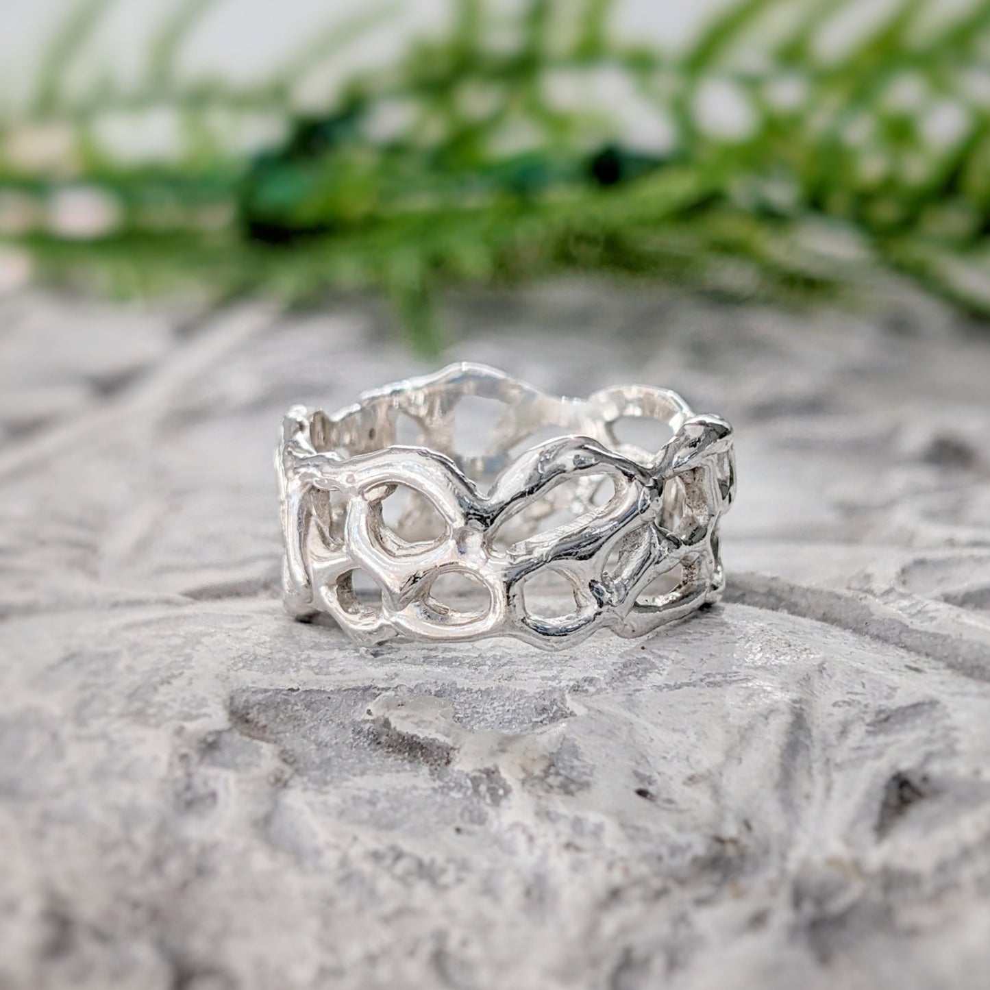Molten Silver Honeycomb ring on a textured surface, showcasing its unique, nature-inspired abstract design.