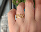 Hand wearing a unique gold honeycomb ring, showcasing its intricate design and natural aesthetic in a close-up view.