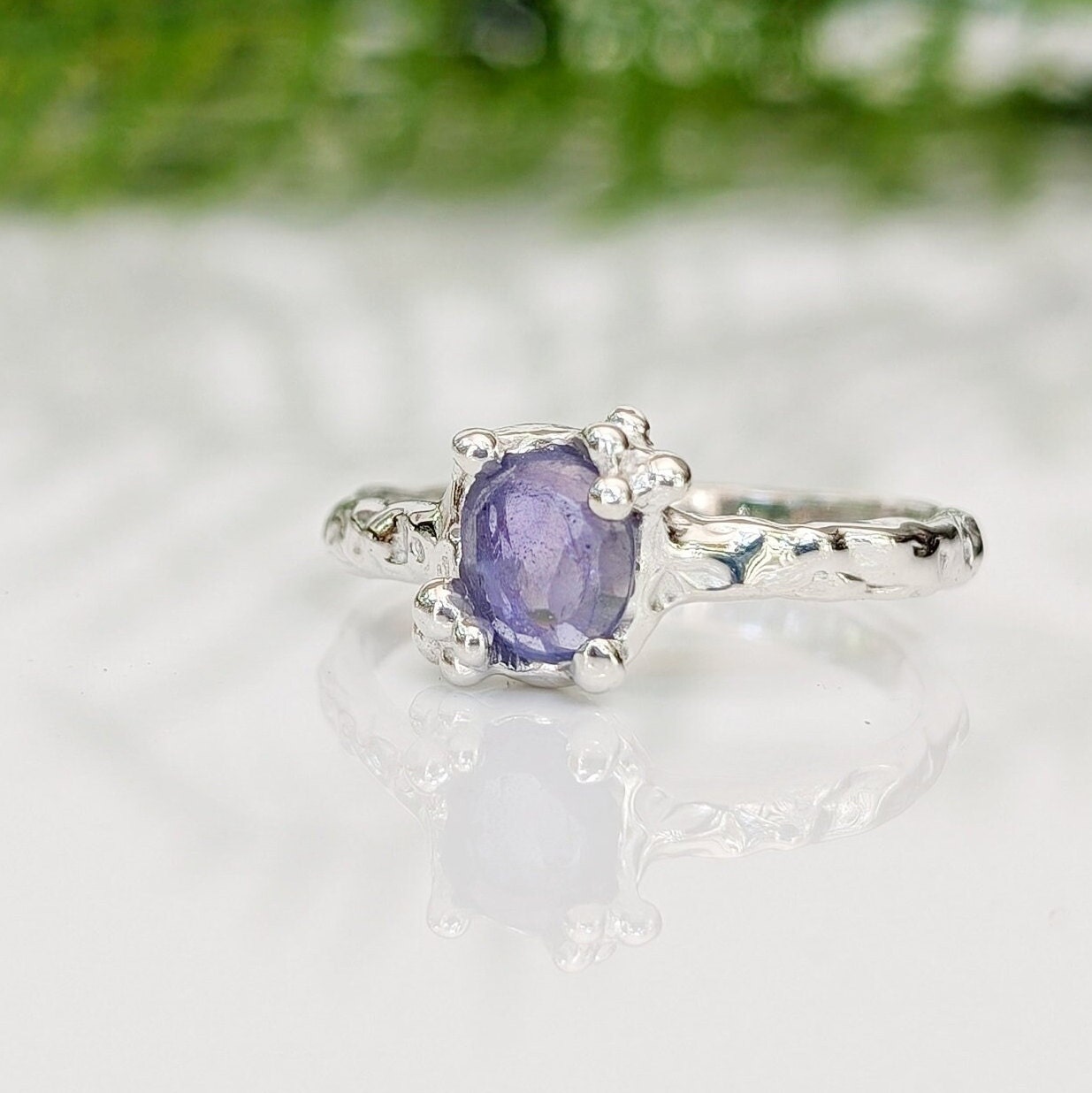 Handcrafted silver Tanzanite ring featuring a textured band and oval purple gemstone, perfect for unique elegance.