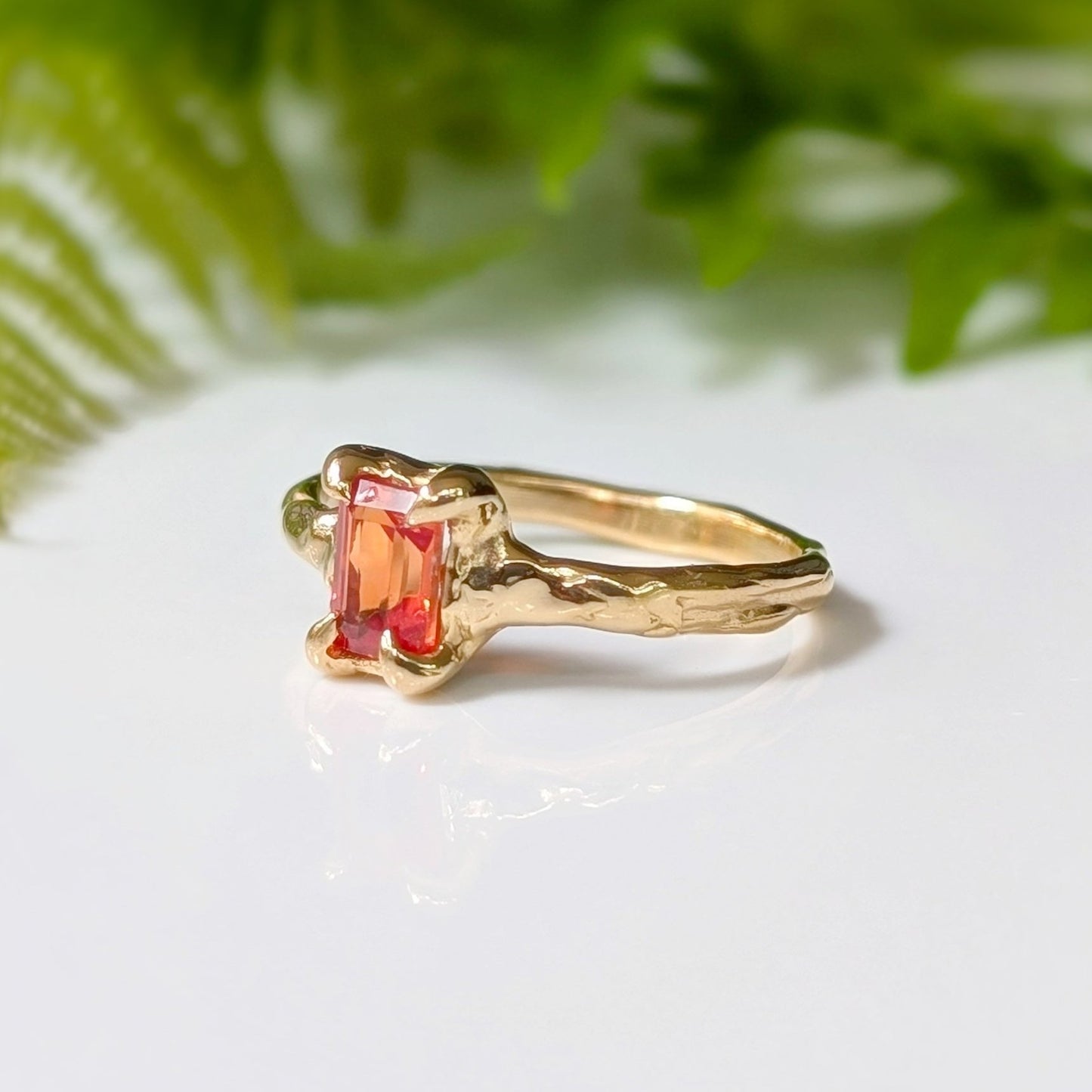 Handcrafted solid 14k gold ring featuring a radiant cut orange sapphire on a textured band.