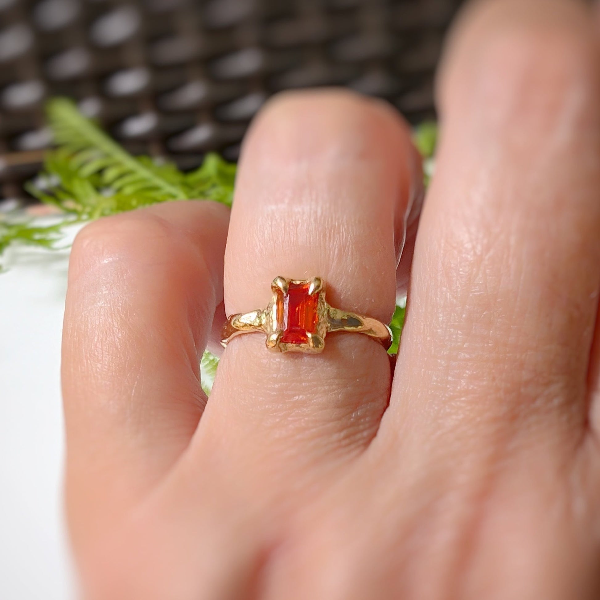 Orange Sapphire textured ring in solid 14k gold worn on a hand, showcasing its unique design and radiant cut stone.