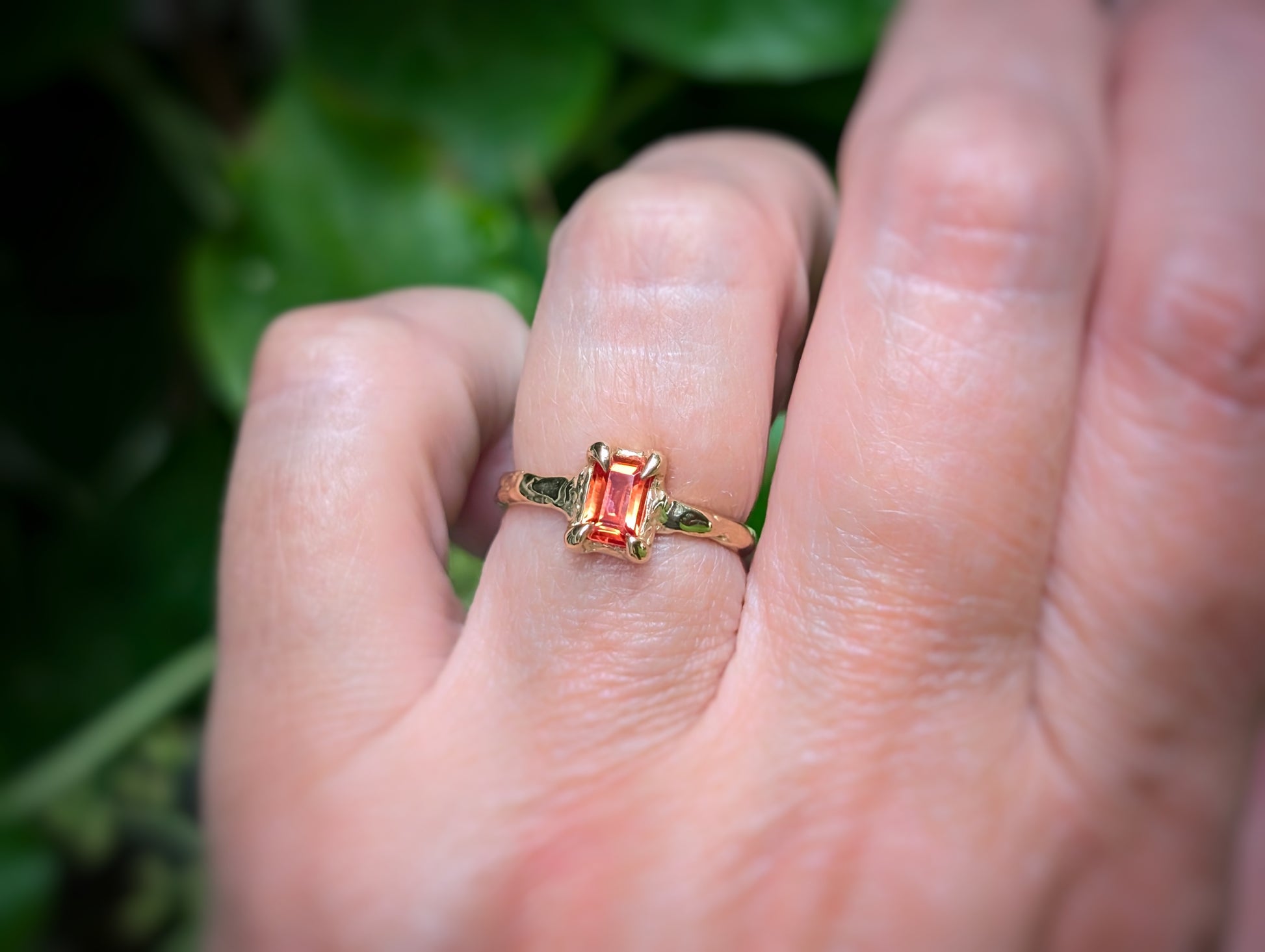 Hand wearing a radiant cut Orange Sapphire textured ring in Solid 14k Gold, showcasing a unique engagement ring design.