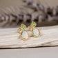 Gold stud earrings with green Peridot and opal stones on a wooden surface