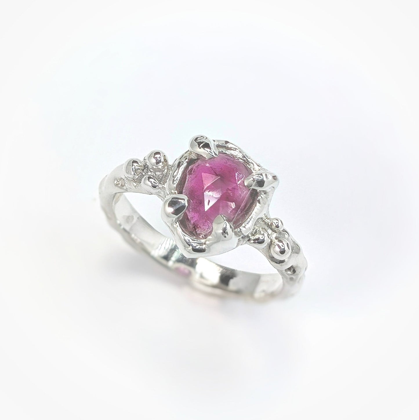 Hand-carved pink sapphire engagement ring in sterling silver featuring a pear shape rose cut stone.