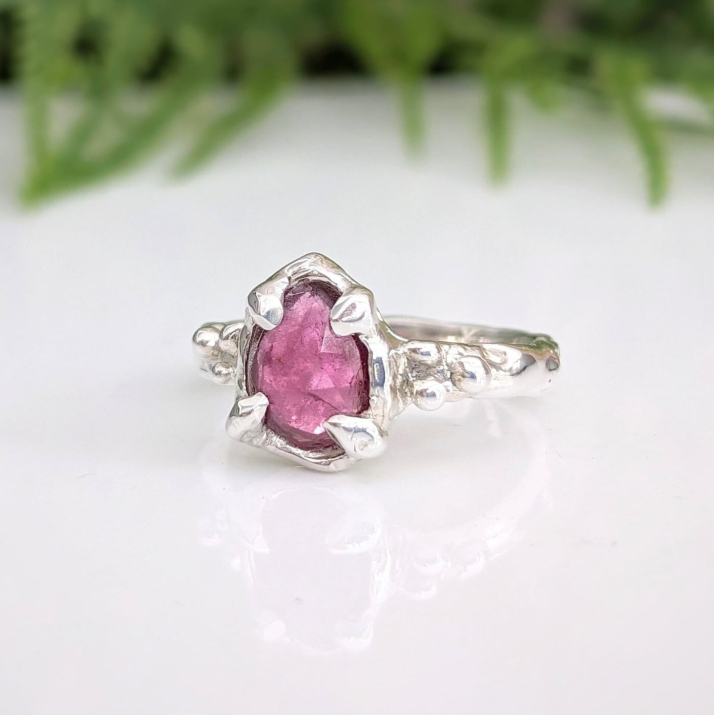 Hand-carved sterling silver ring featuring a pear-shaped rose cut pink sapphire, showcasing unique elegance.