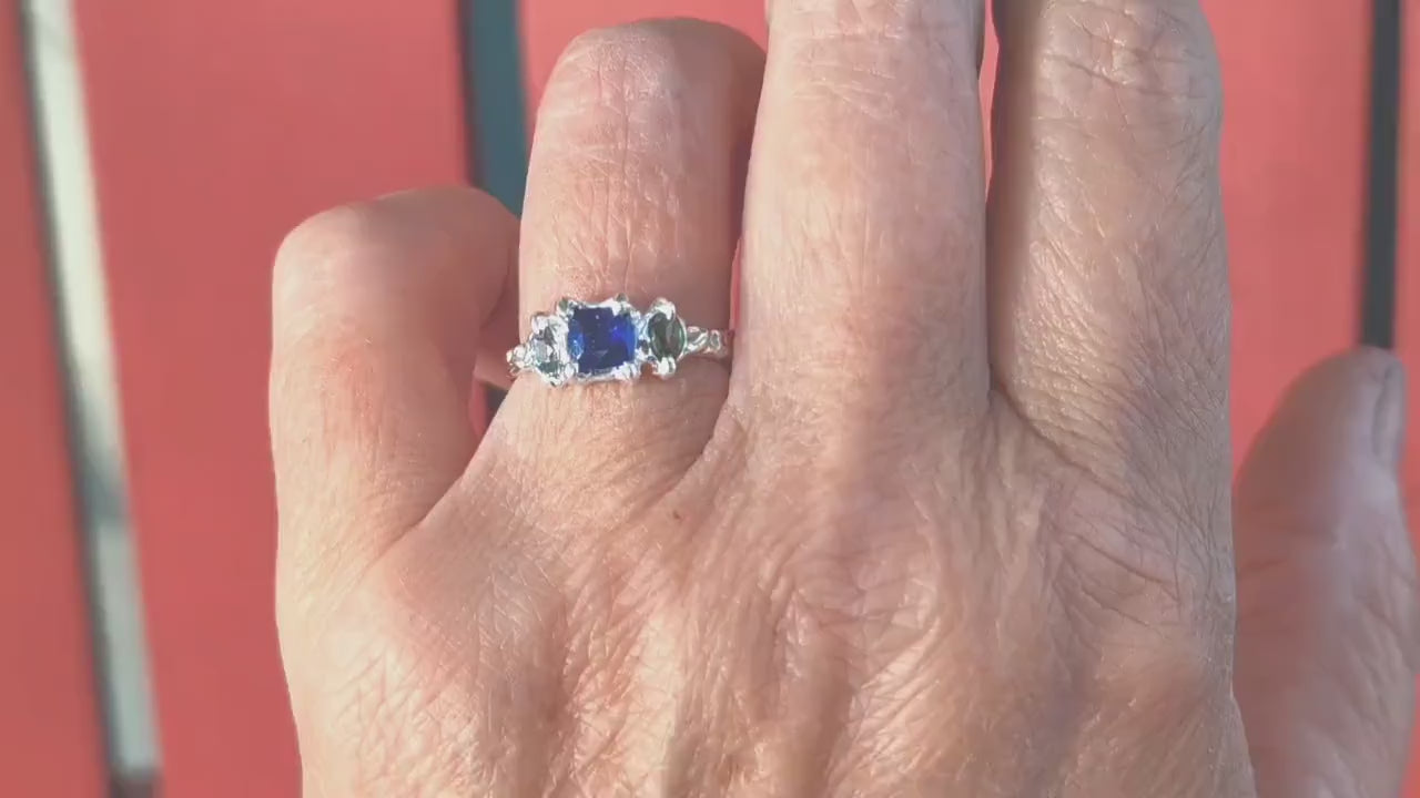 Blue Sapphire and Tourmaline engagement ring in Solid Sterling Silver displayed on a hand.