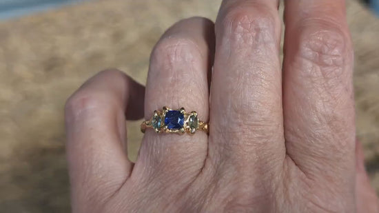 Blue Sapphire and Tourmaline engagement ring in solid 14k gold worn on hand, showcasing elegant rustic design.