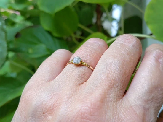 Raw diamond engagement ring on hand, set in solid 14k gold with rustic design and natural crystal.