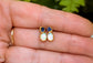 Dainty raw Sapphire and Opal stud earrings in gold setting, showcased in a hand, perfect for bridal or everyday wear.