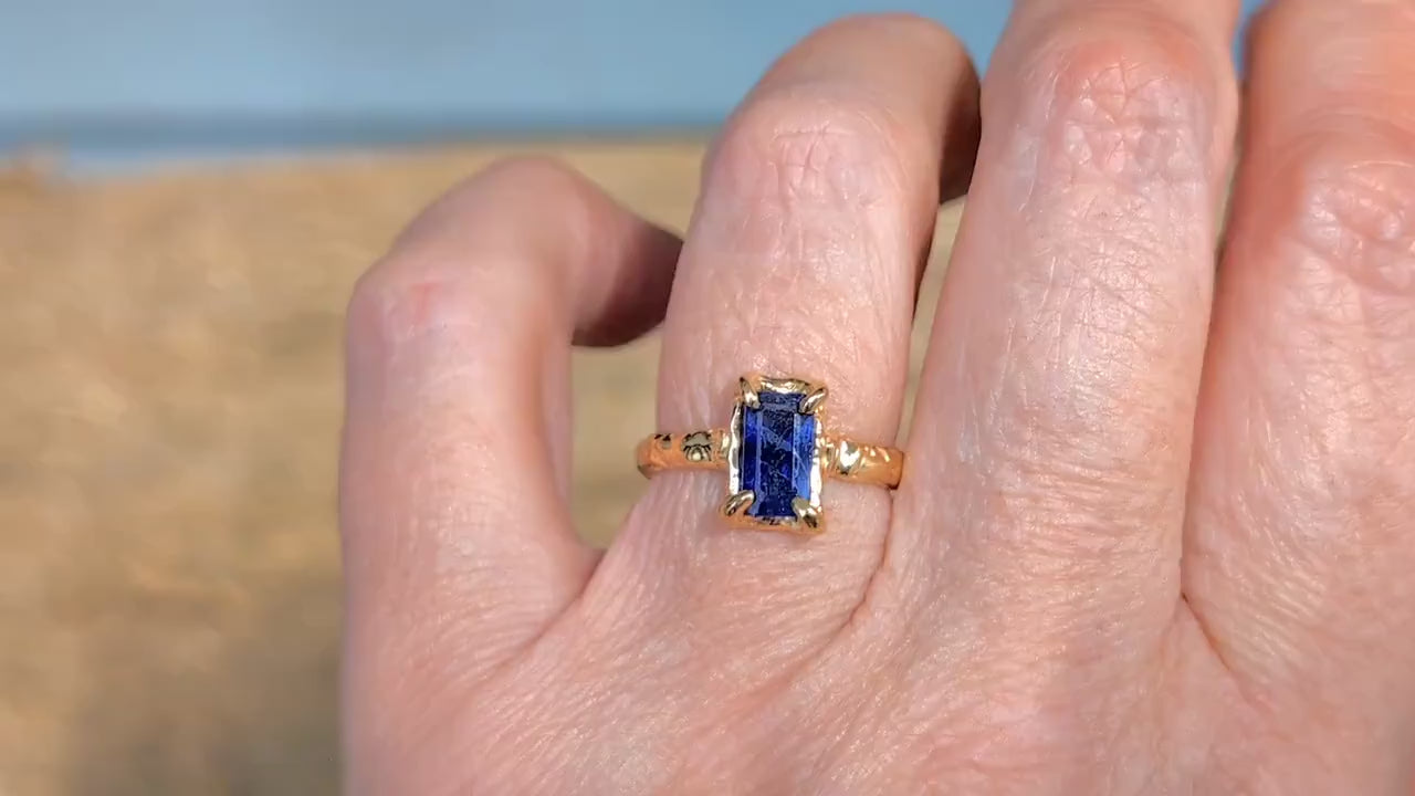 Blue Sapphire cocktail ring in solid 14k gold on a hand, showcasing organic texture and emerald cut design.