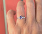 Hand showing a handcrafted Amethyst engagement ring in solid sterling silver with an organic textured band.