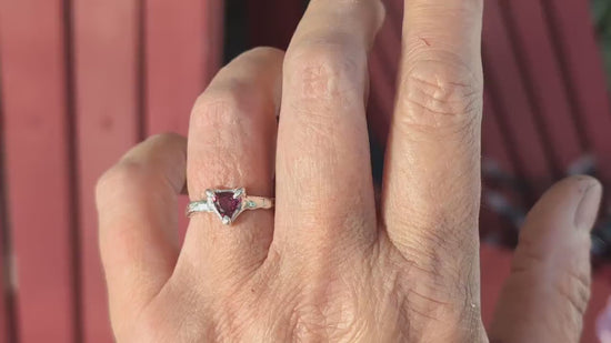 Hand wearing a handcrafted silver ring featuring a dark pink Rubellite Tourmaline stone.
