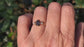 Raw black diamond engagement ring on hand, featuring an uncut black diamond and two smaller raw diamonds.