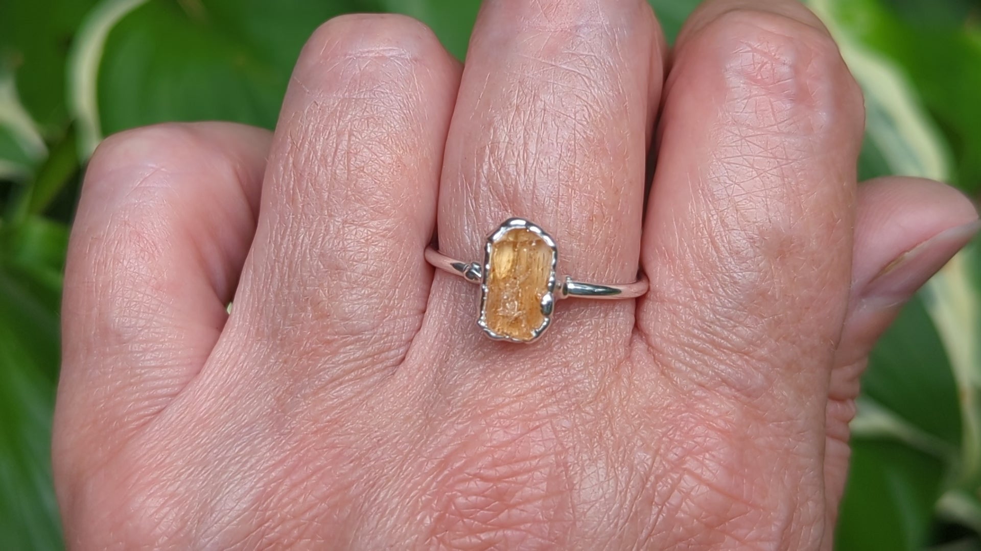Hand wearing a handcrafted Sterling Silver ring featuring a raw Golden Imperial Topaz gemstone.
