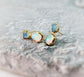 Dainty raw Aquamarine and Opal stud earrings with gold accents on a textured background, elegant and handcrafted.