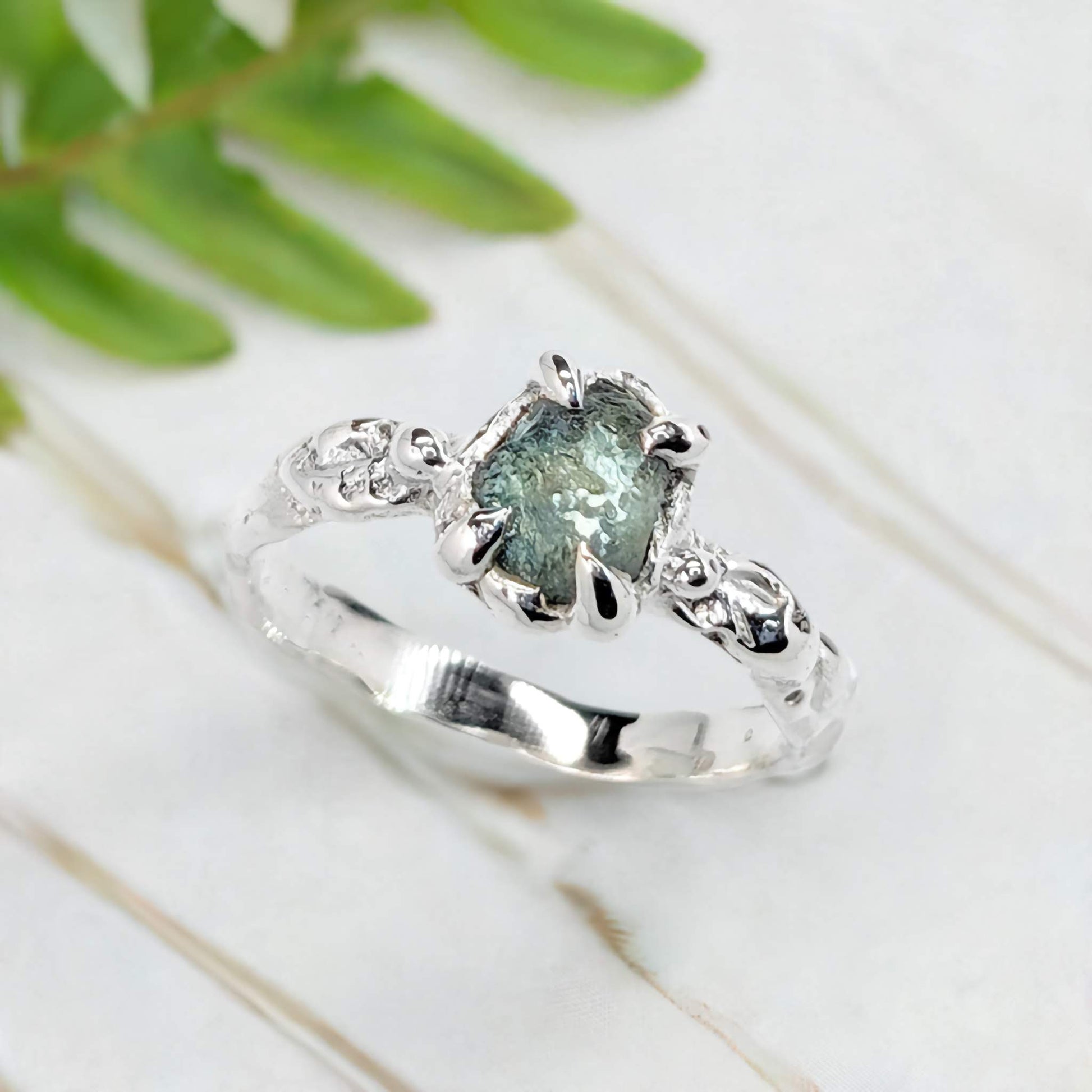 Raw Montana Sapphire engagement ring in solid 14k gold with organic textured band and teal gemstone.