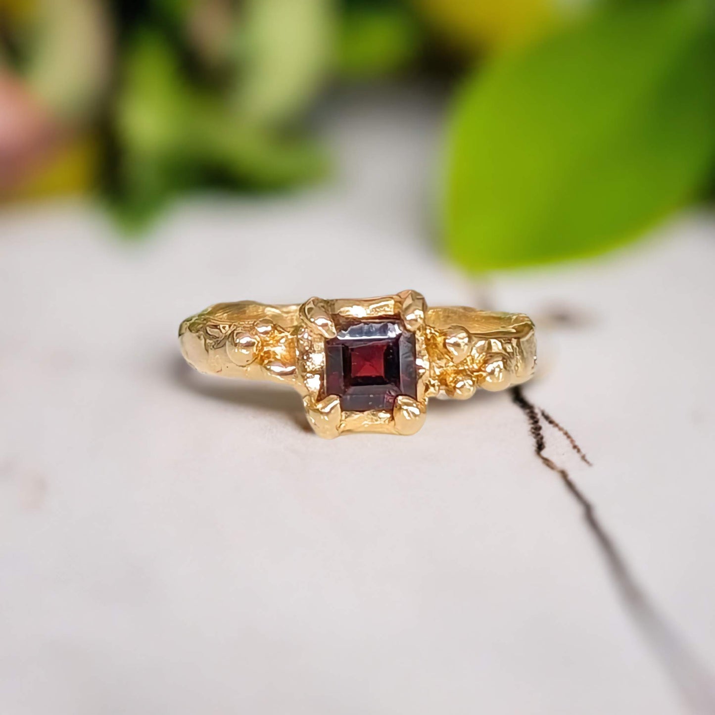 Square red garnet engagement ring in solid 14k gold with an organic textured band.