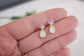 Opal and Amethyst gemstone stud earrings held in a hand with a blurred background