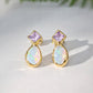 Gold earrings with light purple amethyst and teardrop-shaped opal stones on a light background