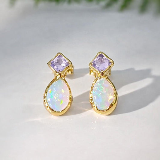 Gold stud earrings with Amethyst and Opal on a light background