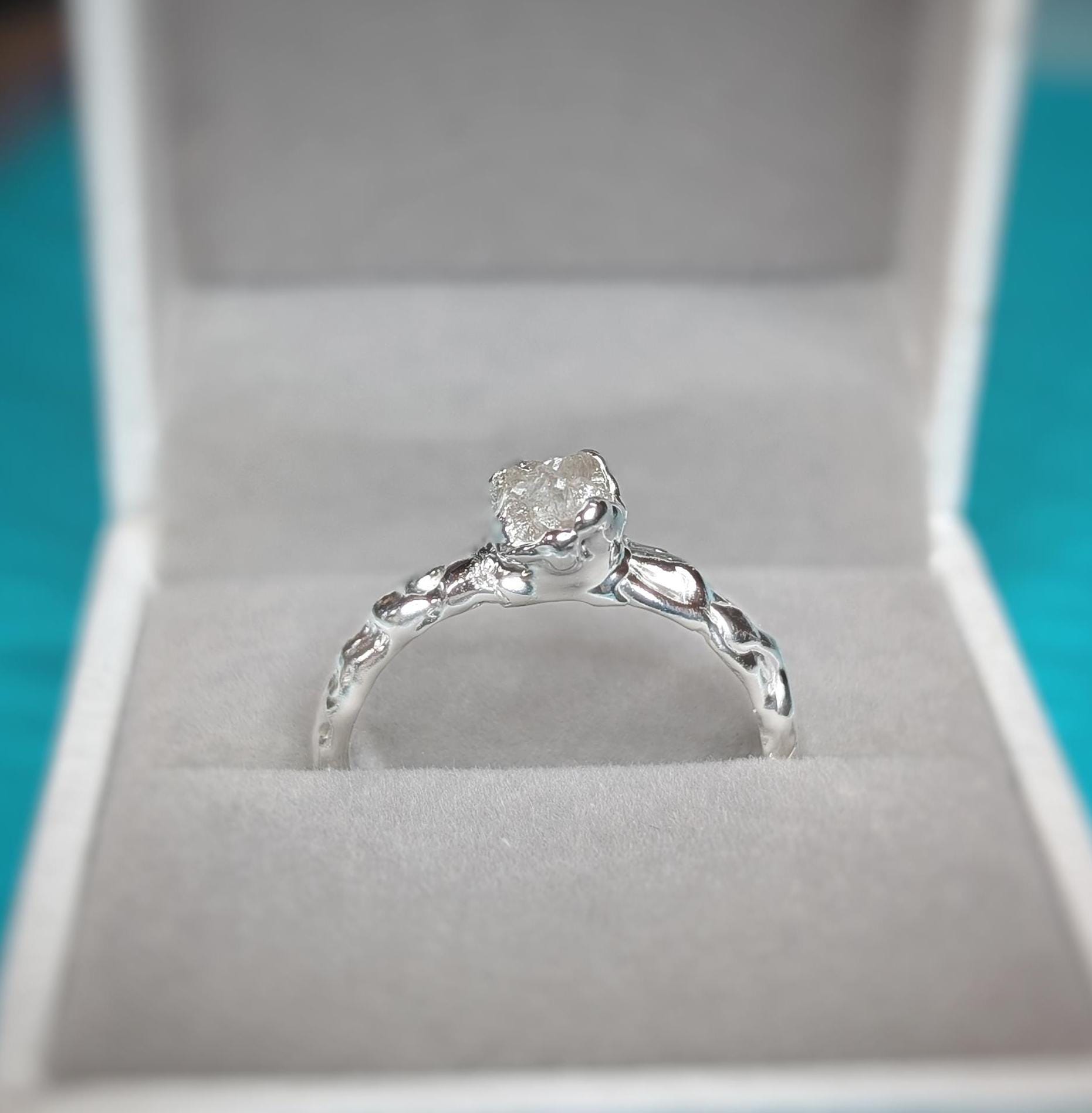 Raw diamond engagement ring in recycled sterling silver showcasing unique molten texture, set in elegant jewelry box.