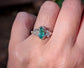 Silver engagement ring featuring a marquise cut emerald and salt & pepper diamonds on a hand.