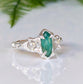 Silver emerald engagement ring with marquise cut emerald and salt & pepper diamonds, nature-inspired design.