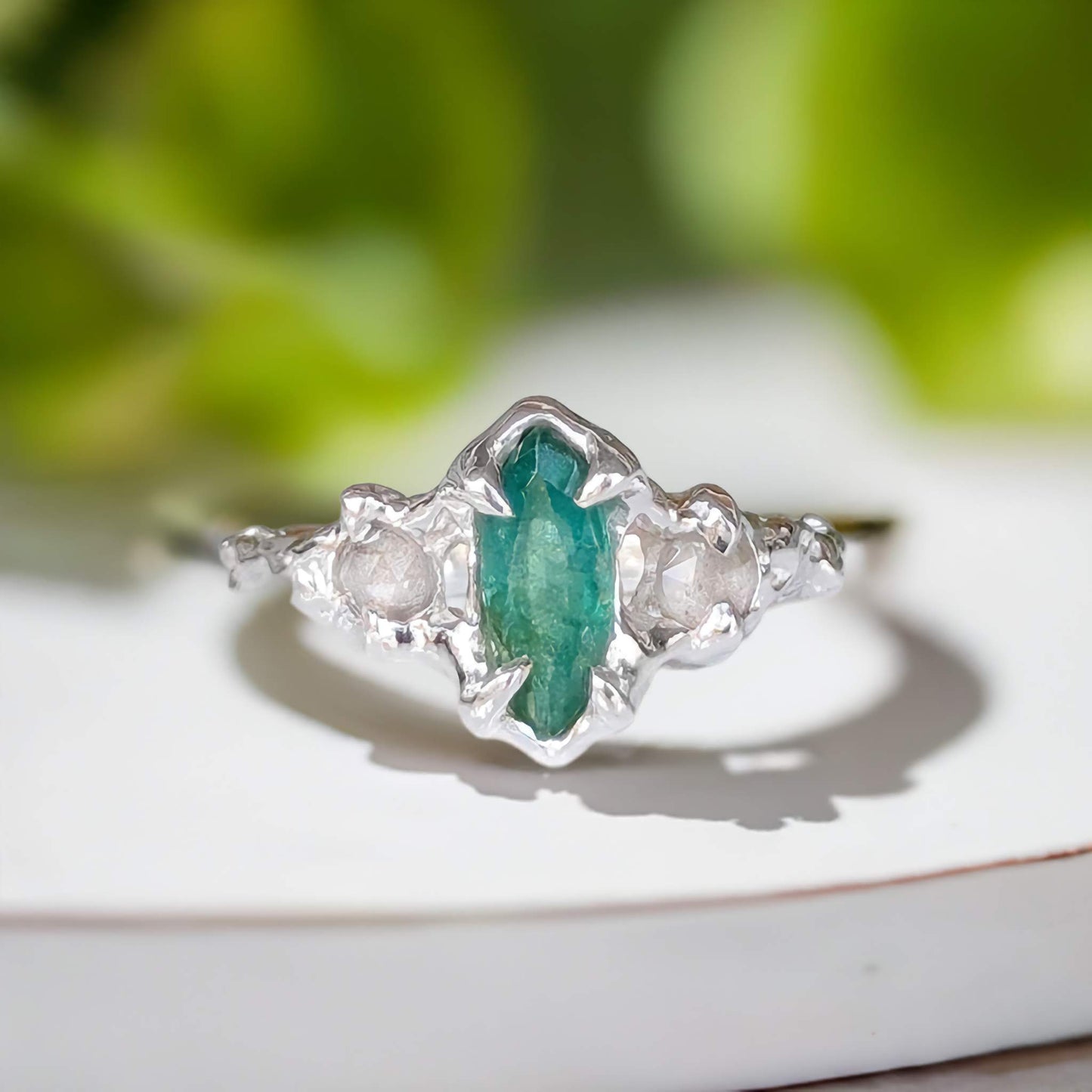 Handcrafted sterling silver engagement ring featuring a marquise cut emerald and two salt & pepper diamonds.