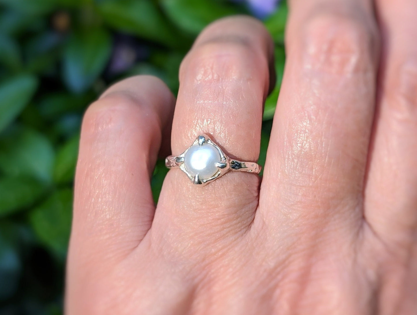 Hand wearing a silver textured ring featuring a creamy-white Freshwater Keshi pearl, perfect for elegance and simplicity.
