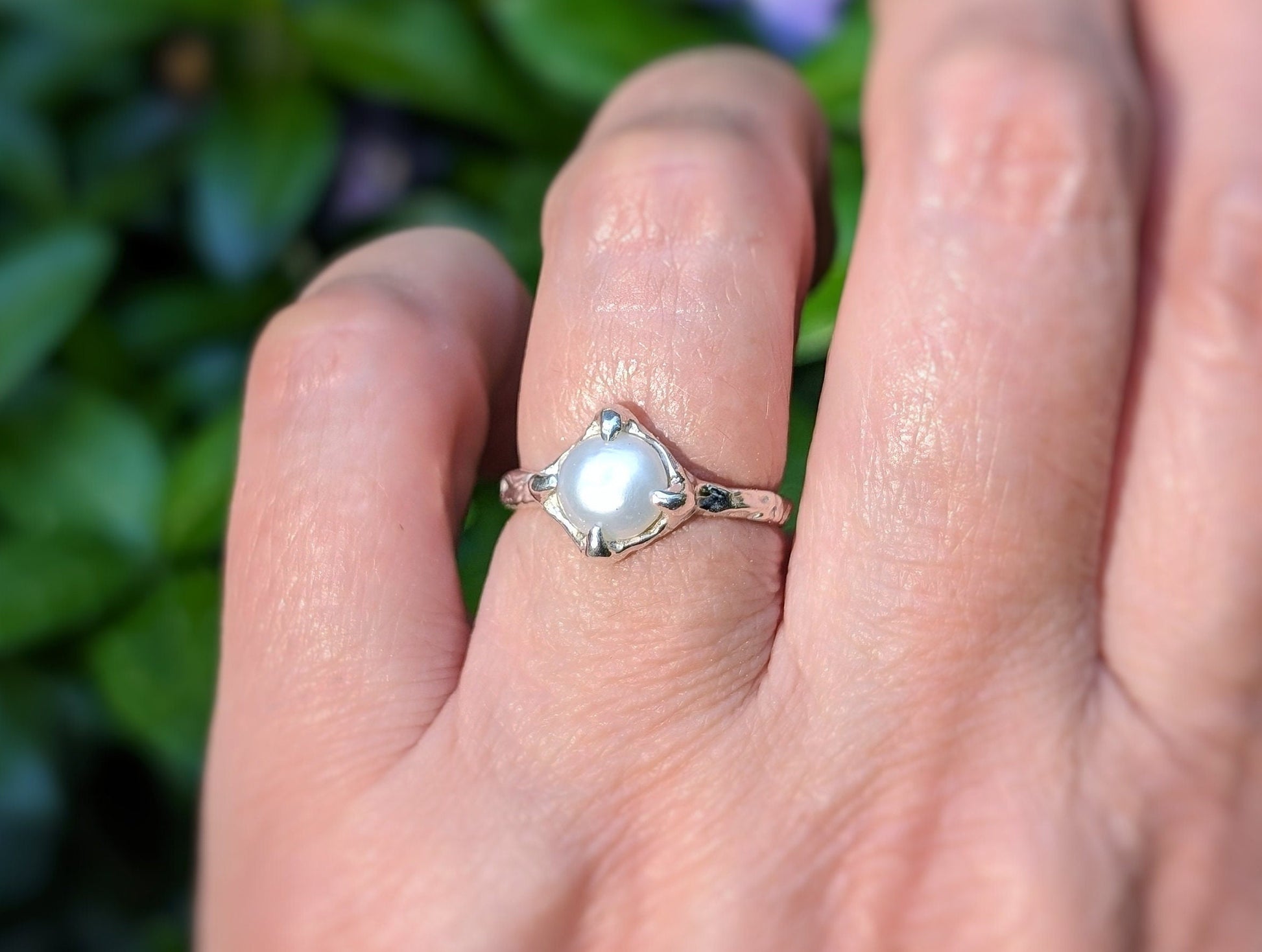 Hand wearing a silver textured ring featuring a creamy-white Freshwater Keshi pearl, perfect for elegance and simplicity.