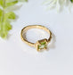 Solid gold Peridot ring with unique textured band and princess-cut green crystal, symbolizing love and individuality.