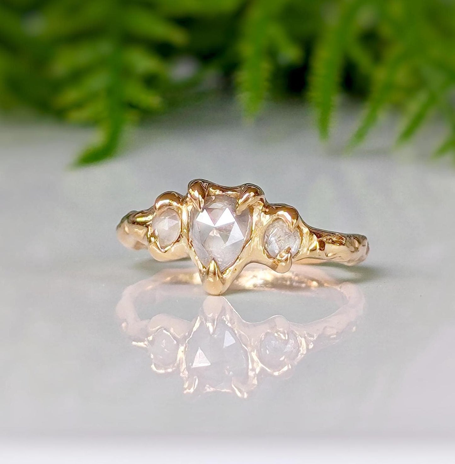 Rustic gold ring featuring a heart-shaped diamond and two side stones, ideal for unique engagement.