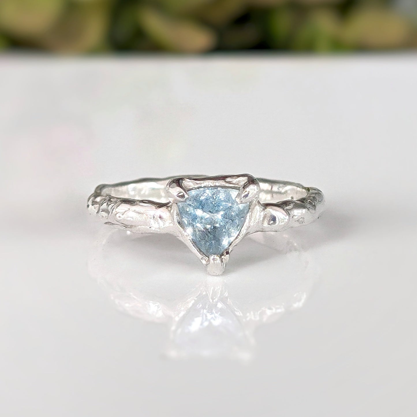 Solid silver aquamarine ring with organic textured band and trilliant cut blue crystal, symbolizing timeless love.