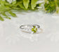 Solid silver Peridot ring featuring a princess-cut green crystal and organic textured band, symbolizing timeless love.