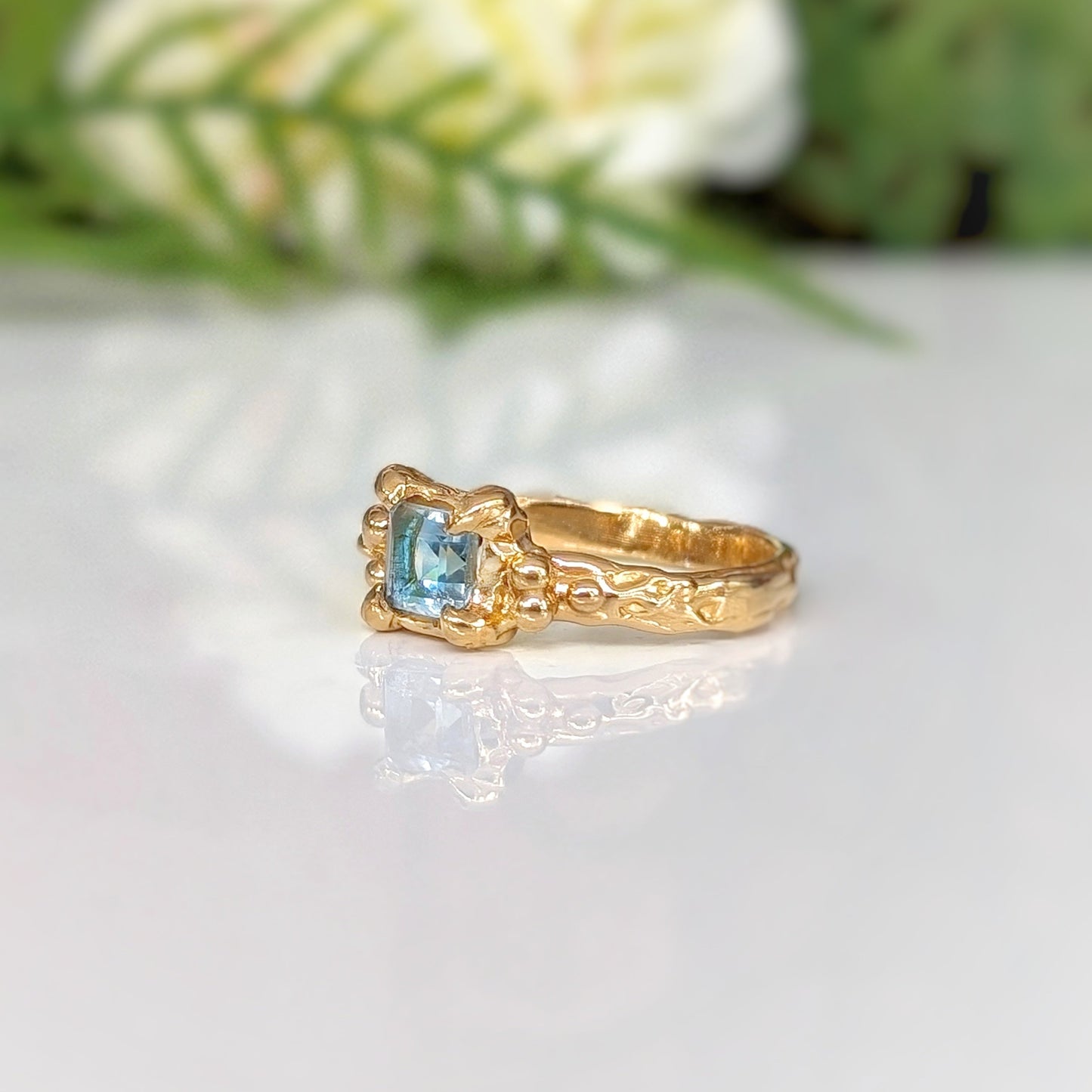 Handcrafted blue topaz engagement ring in organic textured gold, featuring a vibrant blue crystal.