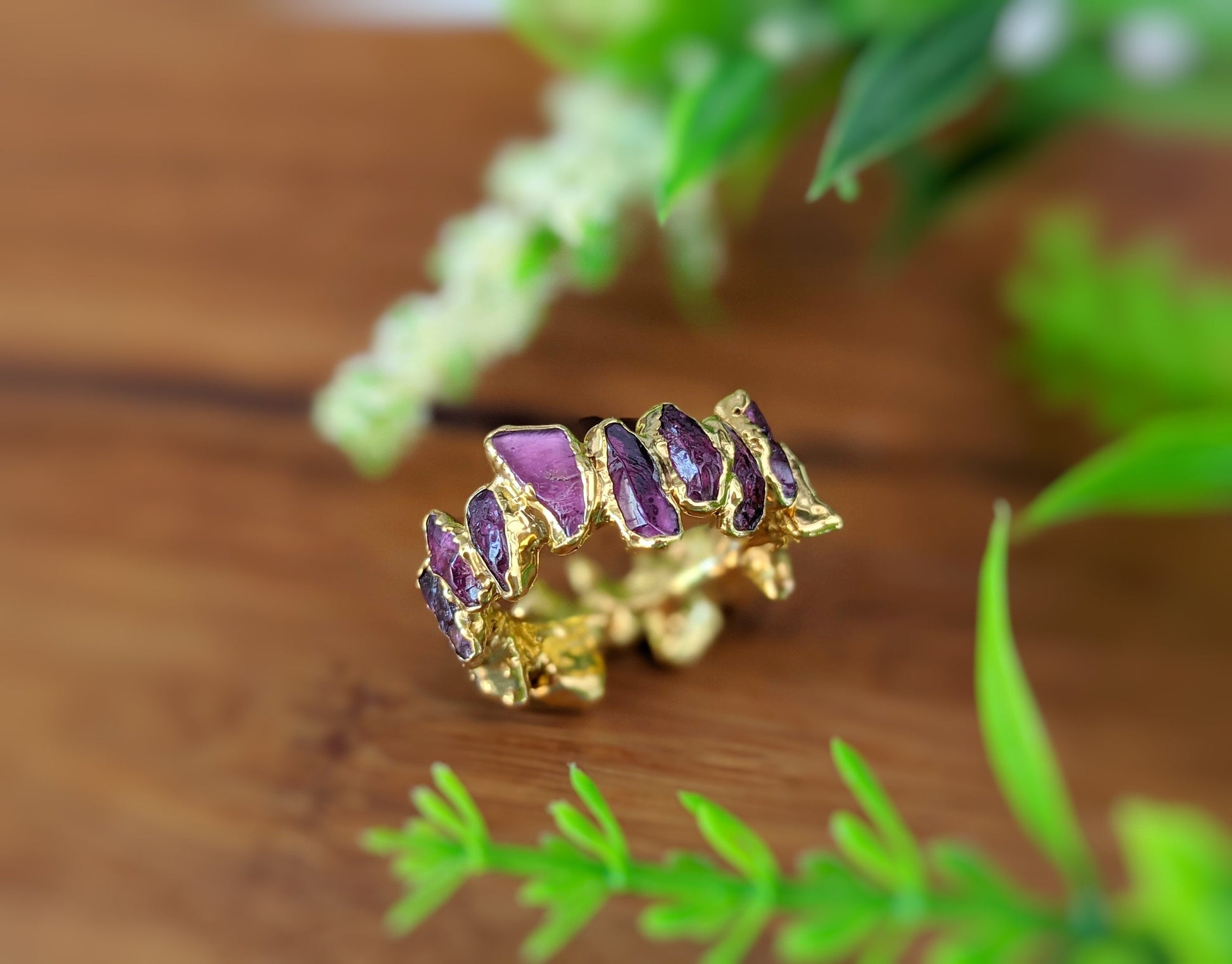 Raw Rhodolite Garnet eternity ring with gold filled band, showcasing unique gemstone shapes and colors.