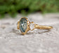 Moss Agate and Herkimer diamond engagement ring on stone background, showcasing pear shape design in 14k gold setting.