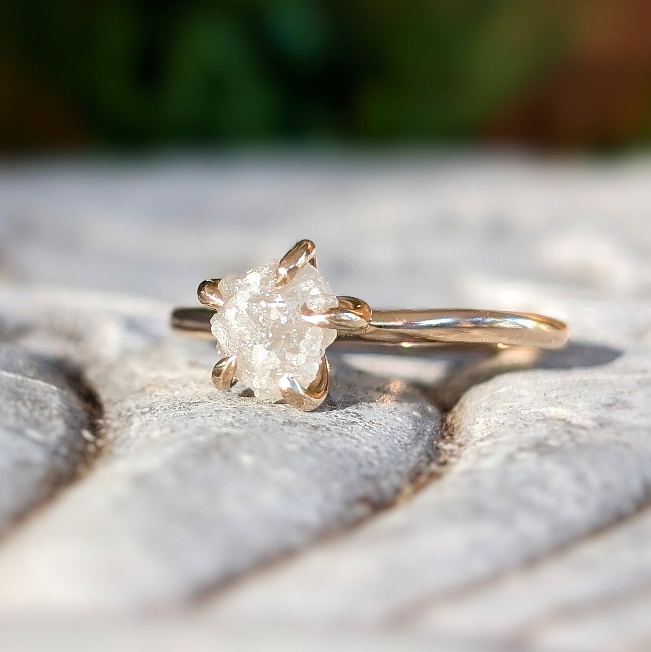 Raw diamond engagement ring in 14k gold setting showcasing uncut diamond's natural beauty.