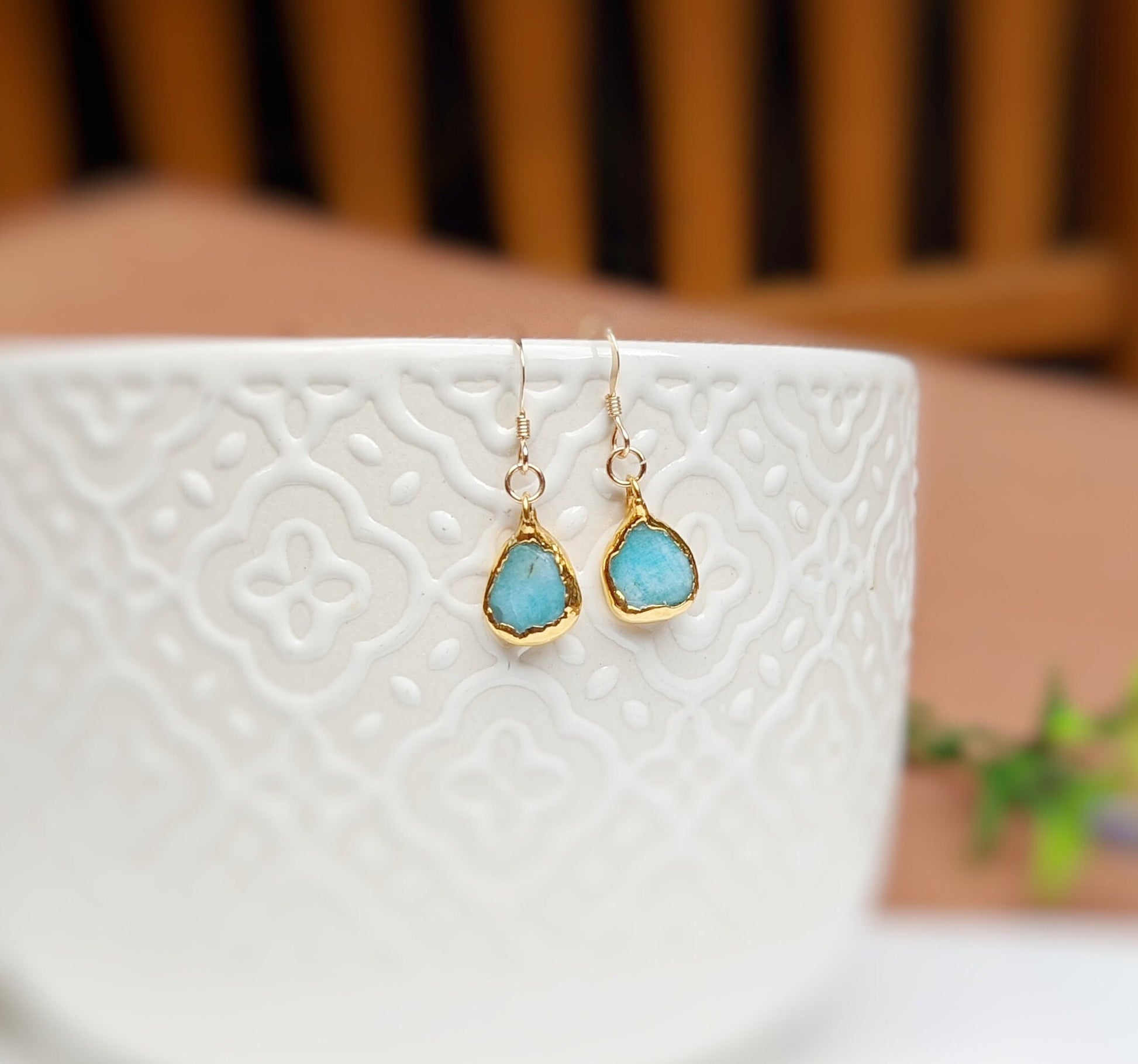 Aqua blue Amazonite dangle earrings with teardrop stones, set in 14k gold filled hooks, displayed by a textured white bowl.