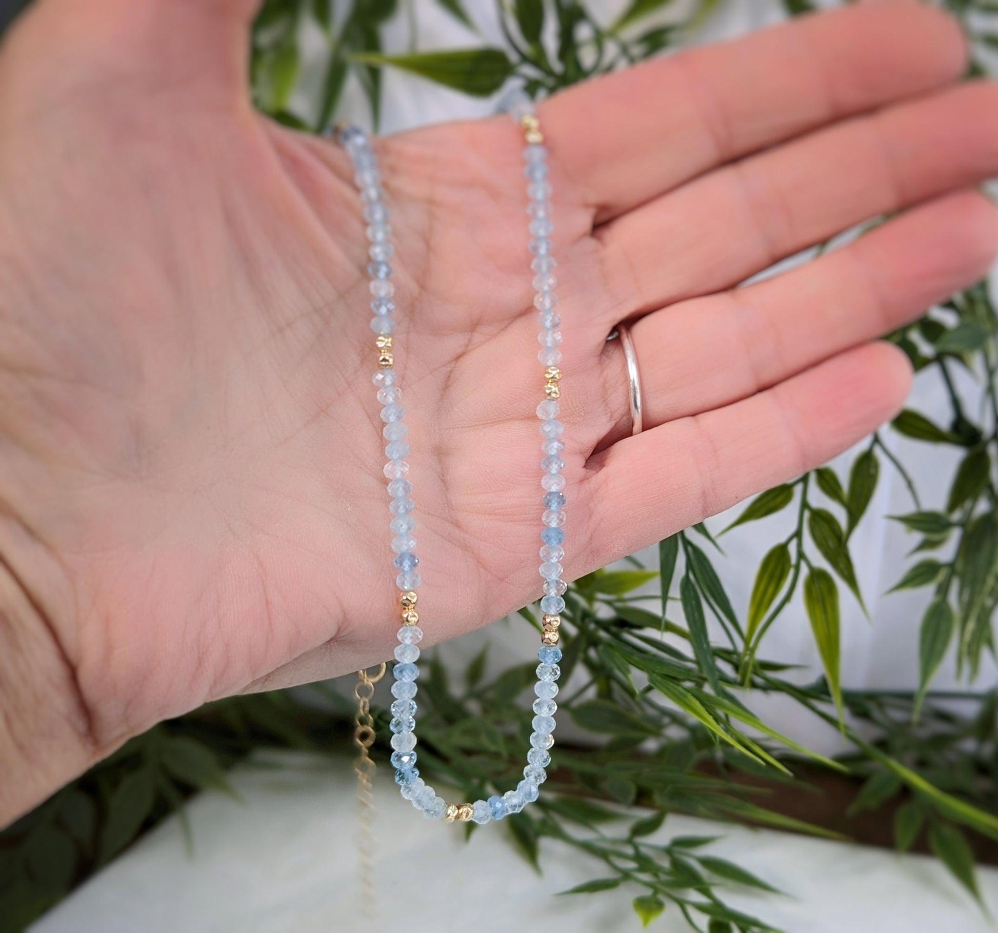 Handmade aquamarine bead necklace with gold accents, showcasing soft blue beads. Perfect gift for serenity and love.