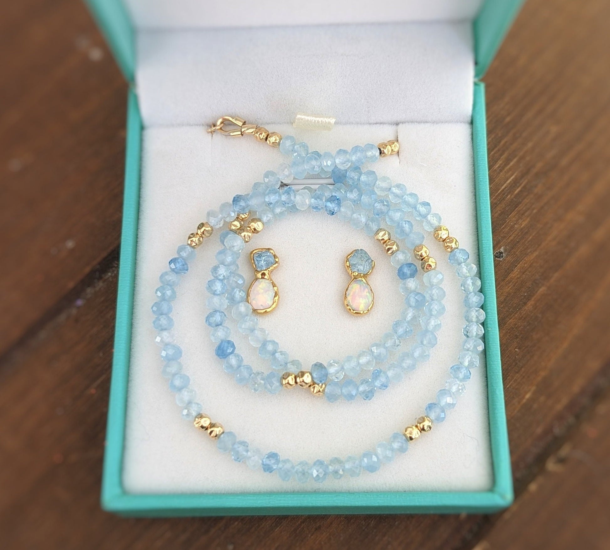Aquamarine and Opal bridal jewelry set in a blue presentation box, featuring earrings and a necklace.
