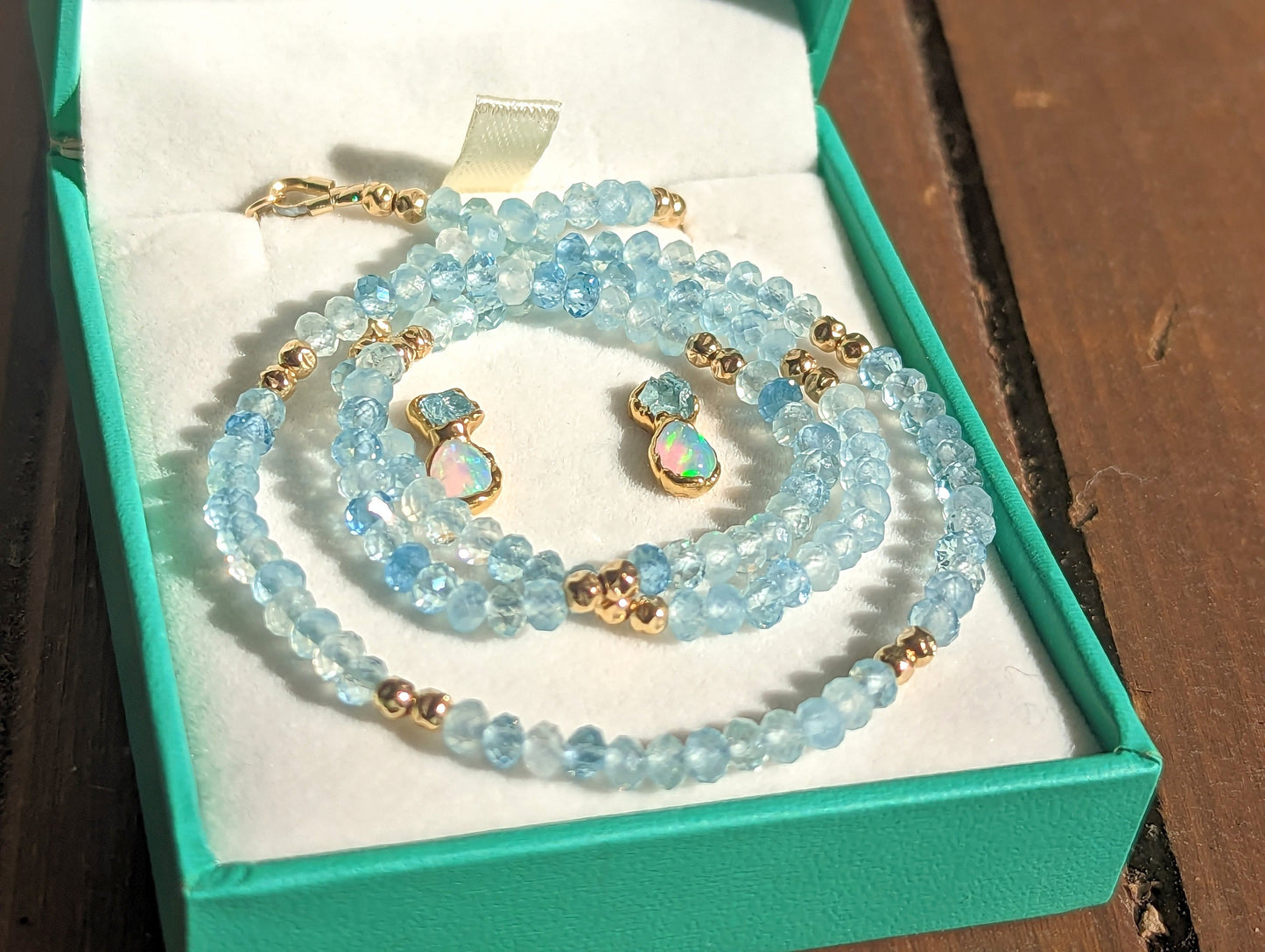 Aquamarine and Opal bridal jewelry set in a teal box, featuring a beaded necklace and stud earrings.