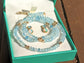 Aquamarine and Opal bridal jewelry set in a teal box, featuring a beaded necklace and stud earrings.