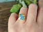 Australian Opal Kintsugi ring on hand, showcasing gold accents and unique blue patterns in a natural setting.
