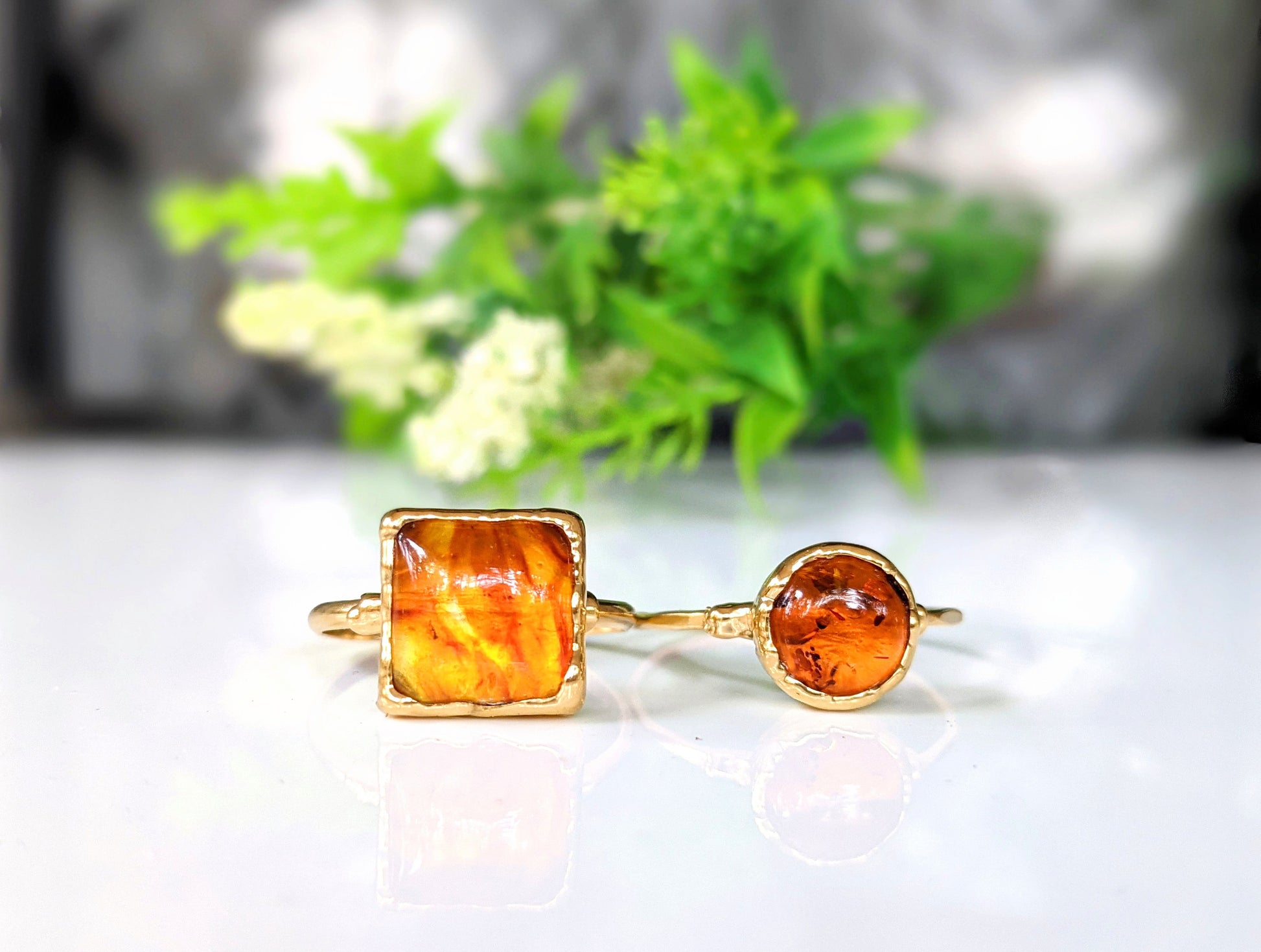 Baltic Amber gold rings featuring unique natural stones on elegant bands, showcasing vibrant hues and individual designs.