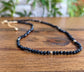Handcrafted Black Spinel bead necklace on wooden surface, perfect for elegant outfits and special occasions.